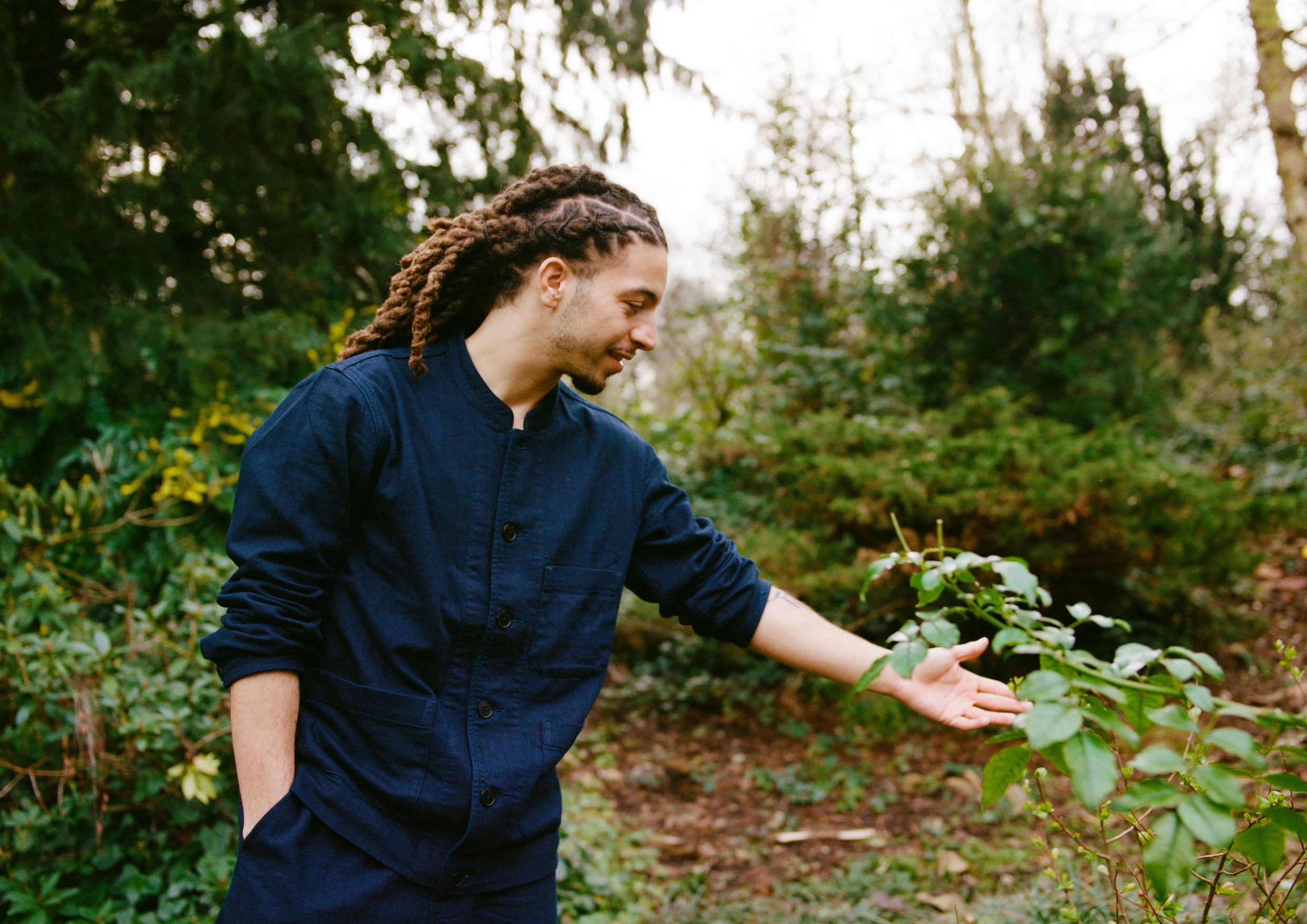 A man in a blue outfit touching a plant
