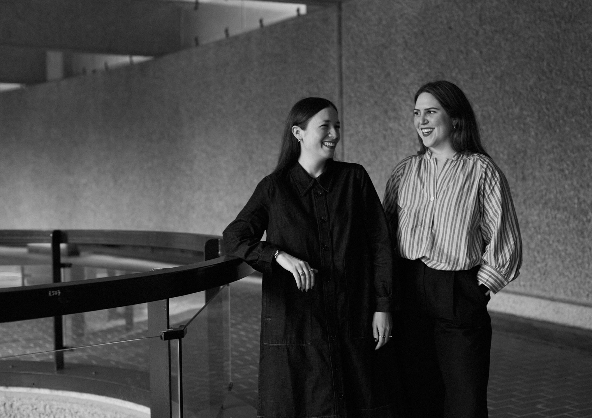 Black and white photograph of two women smiling at each other.