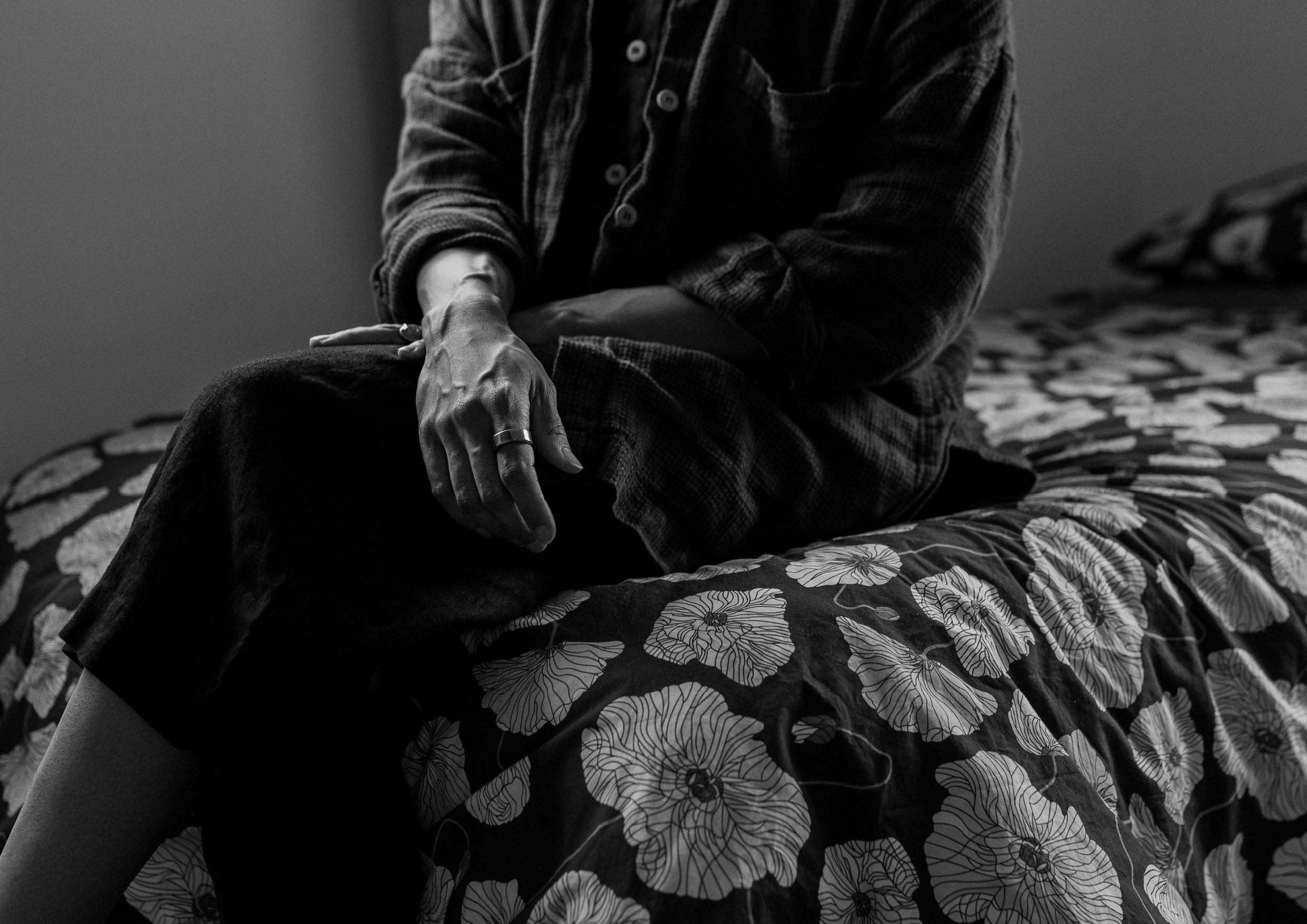 Black and white photograph of woman sat on bed