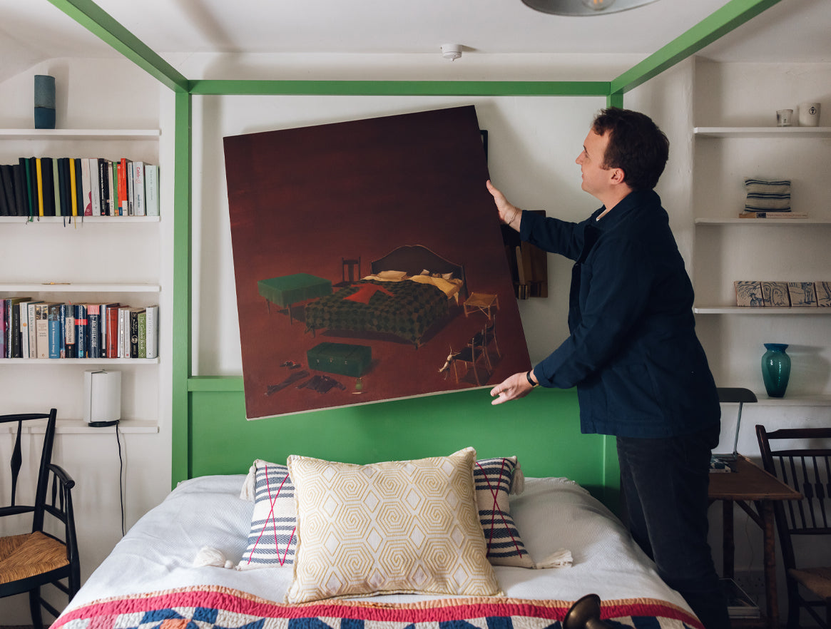 Tobias Vernon hanging a painting in his bedroom in Wells